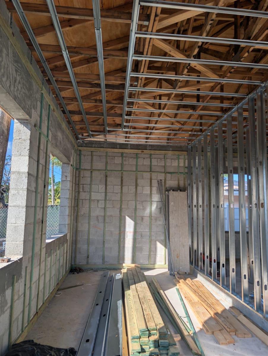 An unfinished room under construction features concrete block walls, metal framing, and exposed wooden trusses — 610 SE 5th Avenue, Pompano Beach FL 33060, POMPANO BEACH, FL