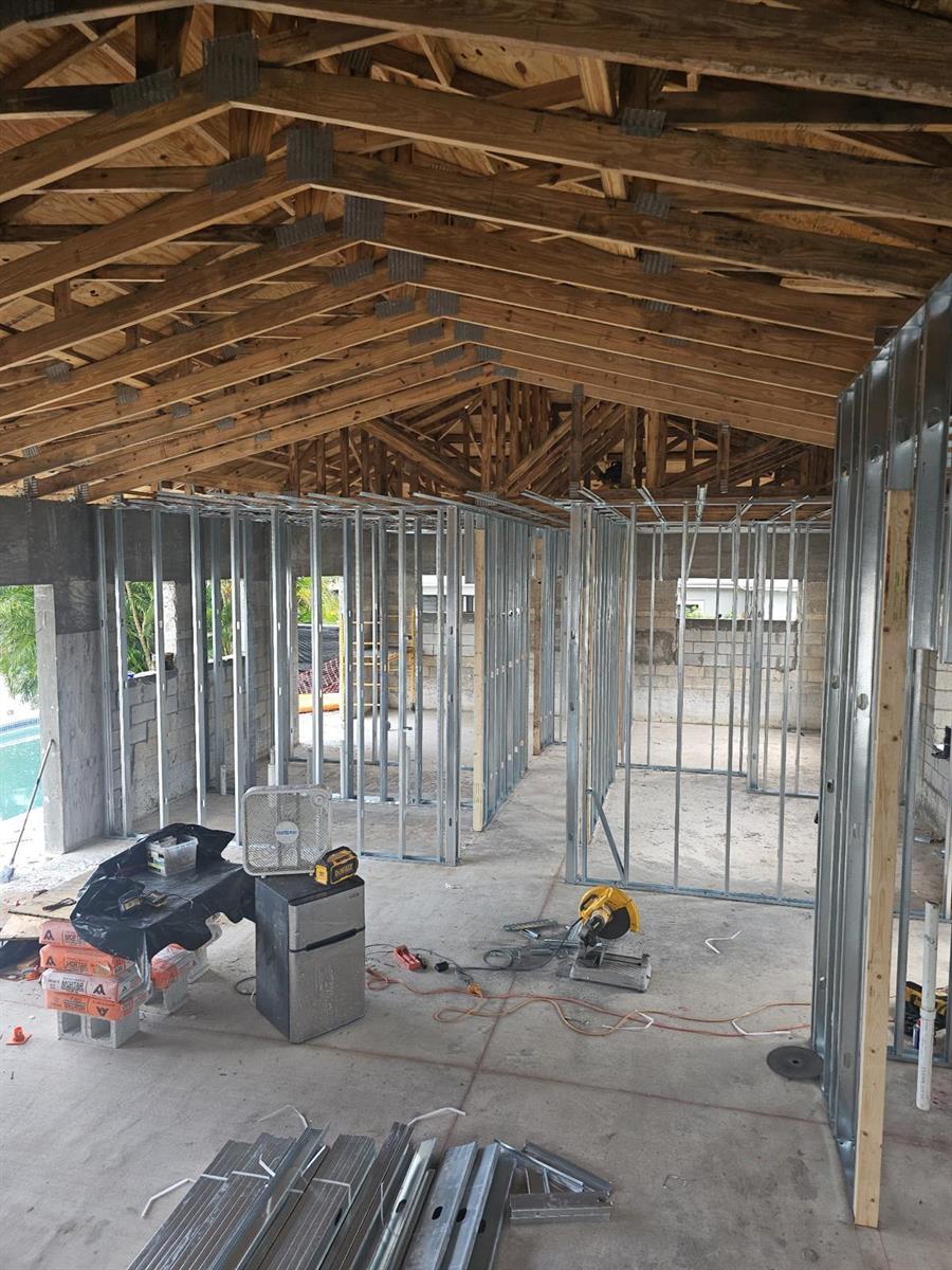 An interior view of a construction site featuring metal wall framing and exposed wooden roof trusses — 610 SE 5th Avenue, Pompano Beach FL 33060, POMPANO BEACH, FL