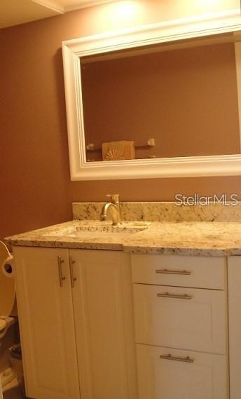 A bathroom vanity with a granite countertop, white cabinets, and a framed wall mirror — 6061 BAHIA DEL MAR BOULEVARD UNIT 110, ST PETERSBURG, FL