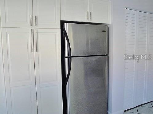A stainless steel refrigerator is positioned between white cabinets and white louvered closet doors — 6061 BAHIA DEL MAR BOULEVARD UNIT 110, ST PETERSBURG, FL