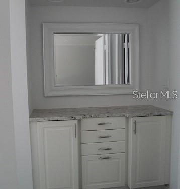 A white bathroom vanity with a granite countertop, four drawers, and a framed wall mirror — 6061 BAHIA DEL MAR BOULEVARD UNIT 110, ST PETERSBURG, FL