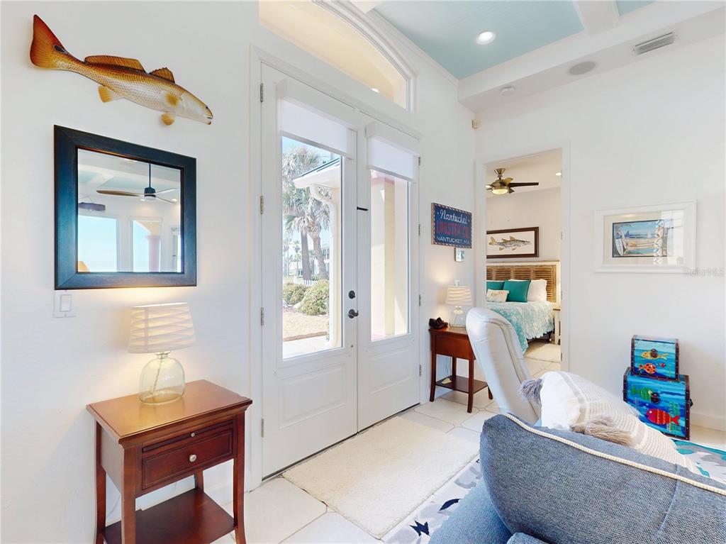 A bright entryway features a wooden side table, a fish wall mount, and a glass door — 811 N ATLANTIC AVENUE, NEW SMYRNA BEACH, FL