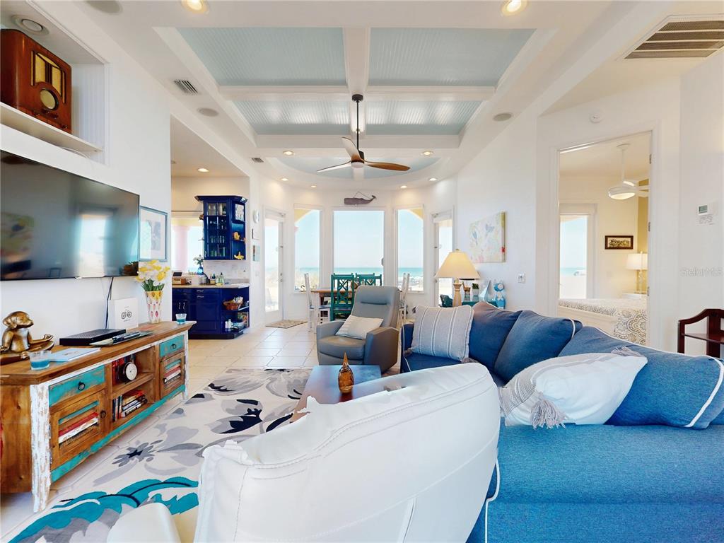 A living room with a blue sectional, a wooden media console, and ocean views — 811 N ATLANTIC AVENUE, NEW SMYRNA BEACH, FL