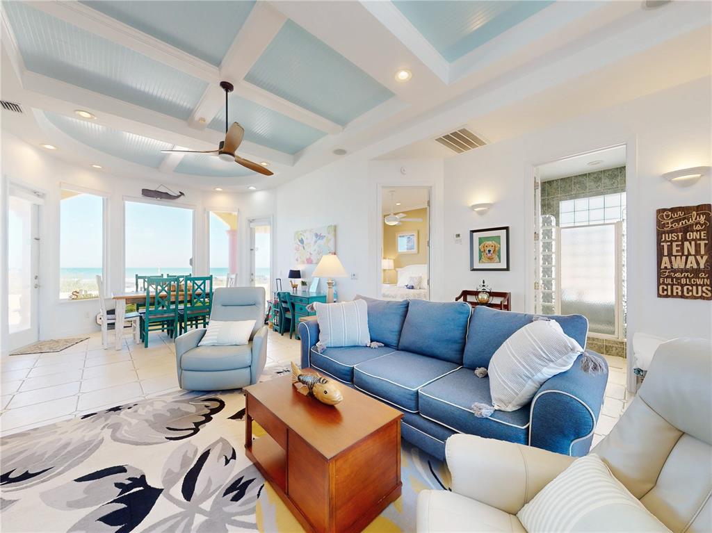 A living room with a blue sofa, coffered ceiling, and a view of the ocean — 811 N ATLANTIC AVENUE, NEW SMYRNA BEACH, FL