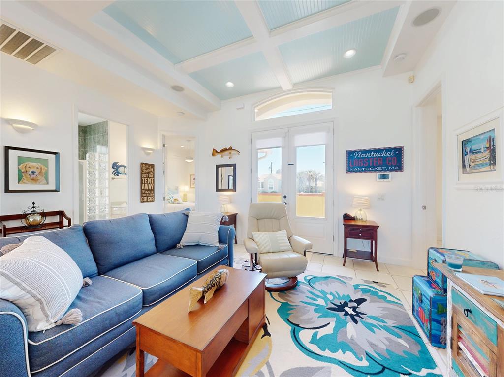A living room features a blue sectional sofa, a patterned rug, and a coffered ceiling — 811 N ATLANTIC AVENUE, NEW SMYRNA BEACH, FL