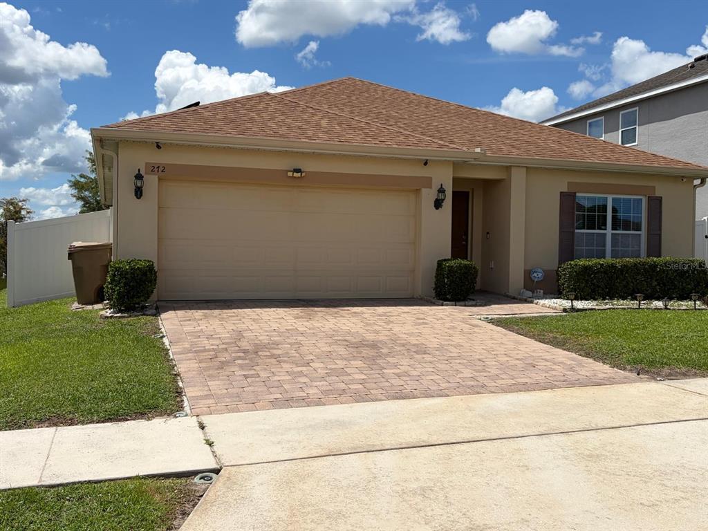 A single-story house with a tan stucco exterior, a paved driveway, and a two-car garage — 272 SPARROW HAWK DRIVE, GROVELAND, FL