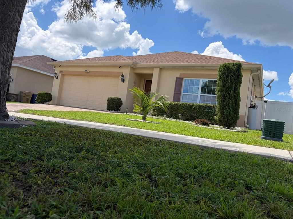 A single-story tan house with a two-car garage and a manicured lawn — 272 SPARROW HAWK DRIVE, GROVELAND, FL