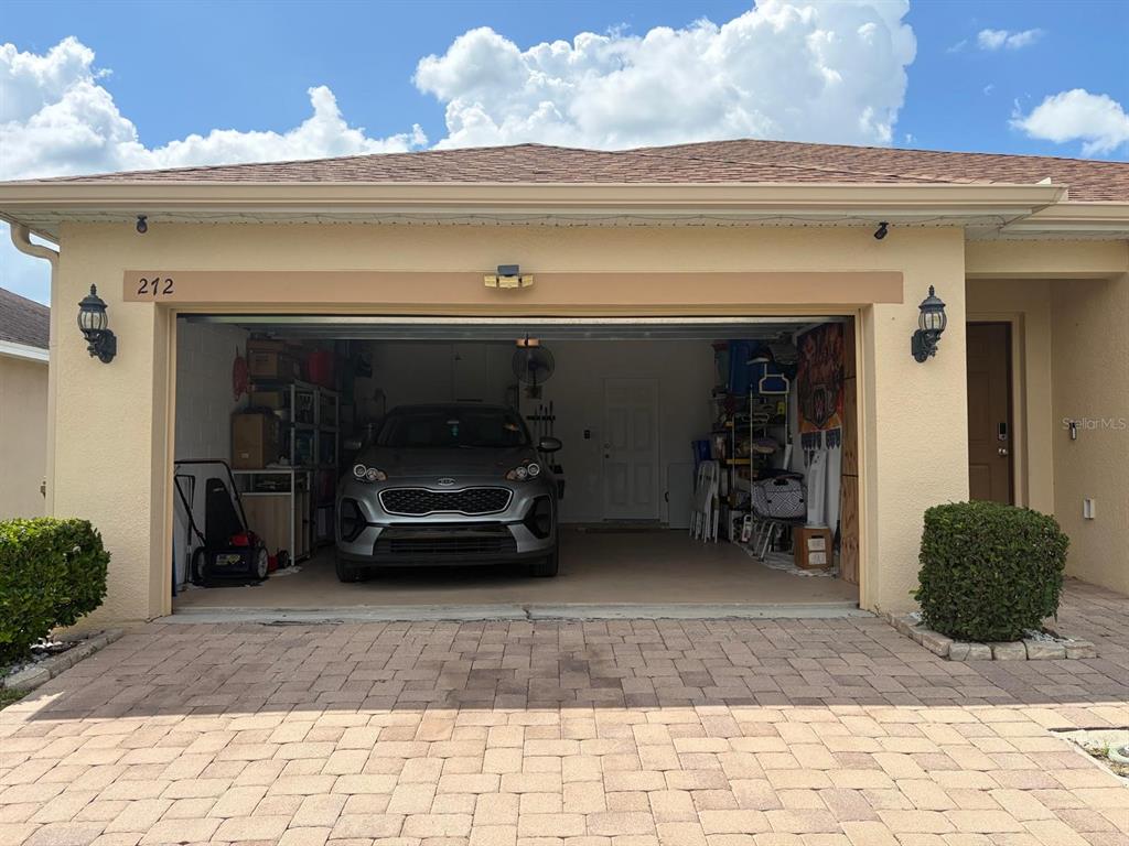 A beige house exterior features a two-car garage with a parked SUV and paver driveway — 272 SPARROW HAWK DRIVE, GROVELAND, FL