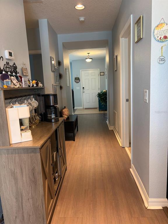 A hallway features wood-look flooring, a coffee station on a cabinet, and a front door — 272 SPARROW HAWK DRIVE, GROVELAND, FL