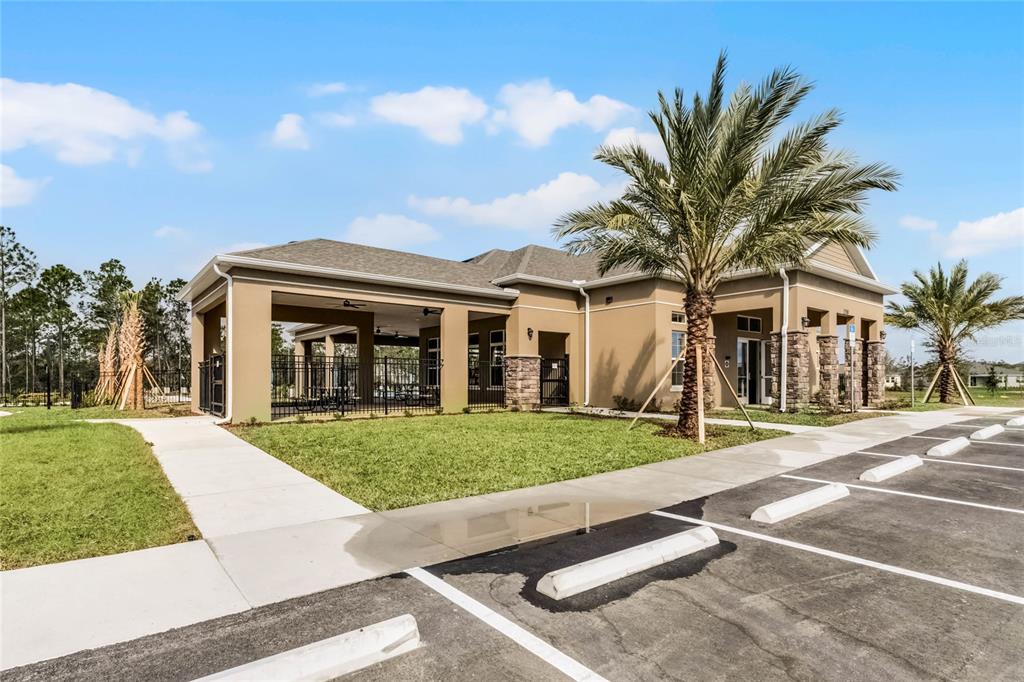 A tan community center building features a covered patio, palm trees, and a parking lot — 3024 KINGSMAN TRAIL, ORMOND BEACH, FL