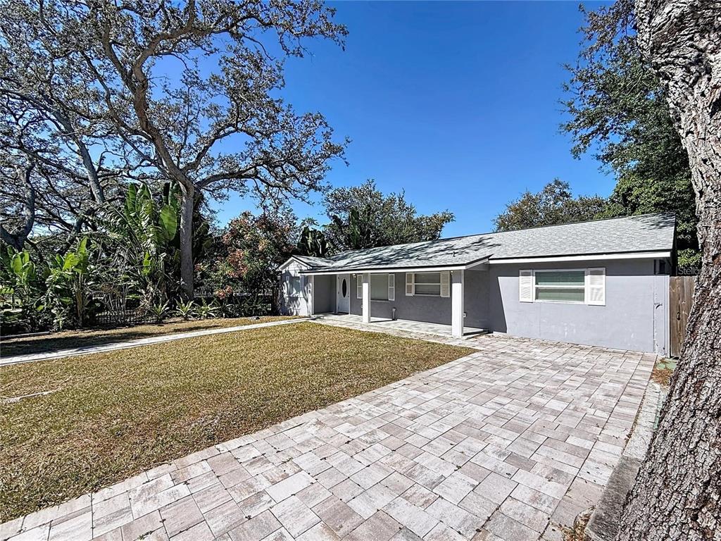 A single-story gray house with a paved driveway and a front porch under a tree — 1408 ROGERS STREET, CLEARWATER, FL