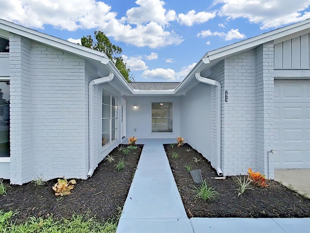 A light gray brick house exterior features a central walkway leading to the front entrance — 7513 MAYFAIR COURT, TAMPA, FL