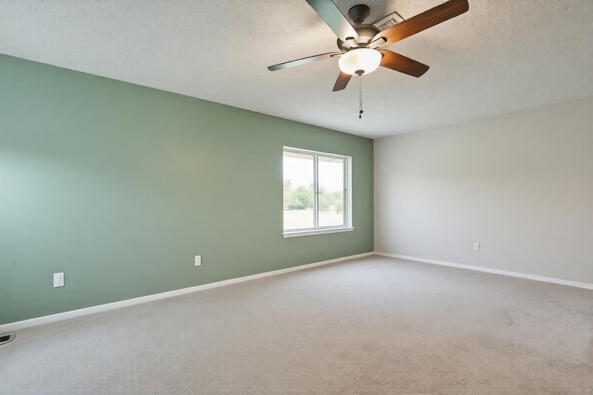 An empty bedroom features a green accent wall, beige carpet, and a ceiling fan — 6309 Summer Sky Lane, FL 33463, FL