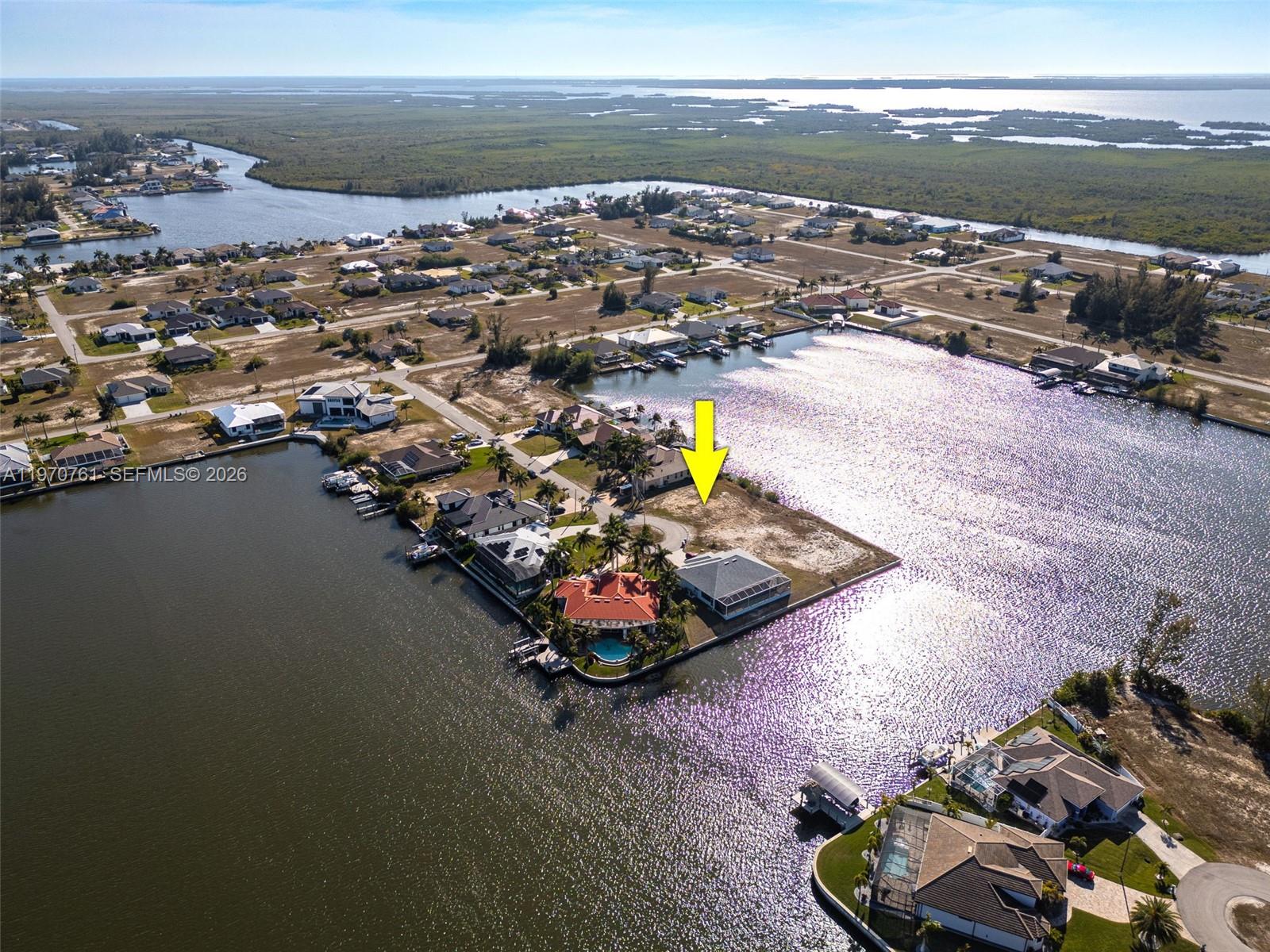An aerial view shows a vacant waterfront lot marked by a yellow arrow — 2826 NW 43rd, Cape Coral FL 33993, CAPE CORAL, FL
