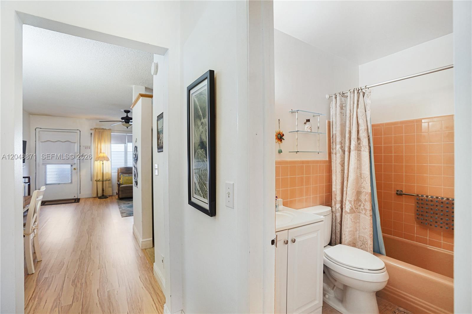 A bathroom with peach-colored tiles and a shower curtain sits beside a hallway entrance — 820 SW 11th Ave # 18B, Hallandale Beach FL 33009, HALLANDALE BEACH, FL