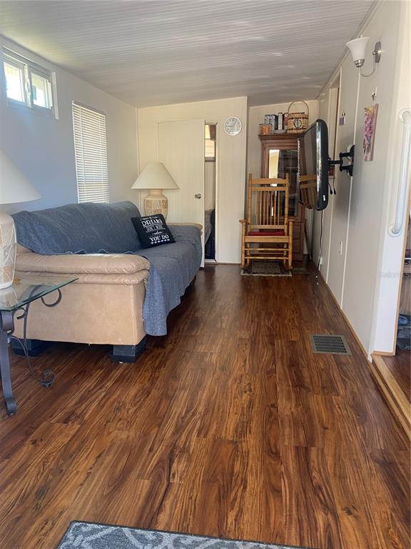 A living room features wood-look flooring, a tan sofa with a blue throw, and a rocking chair — 4812 ELWANA WAY, ZEPHYRHILLS, FL