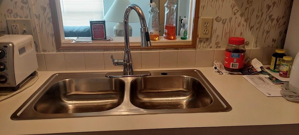 A stainless steel double-basin kitchen sink with a chrome faucet sits on a white countertop — 4812 ELWANA WAY, ZEPHYRHILLS, FL