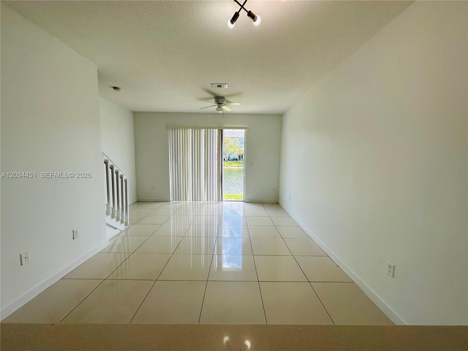 A bright living room features large beige floor tiles, white walls, and a sliding glass door — 3507 NW 13th St, Lauderhill FL 33311, LAUDERHILL, FL