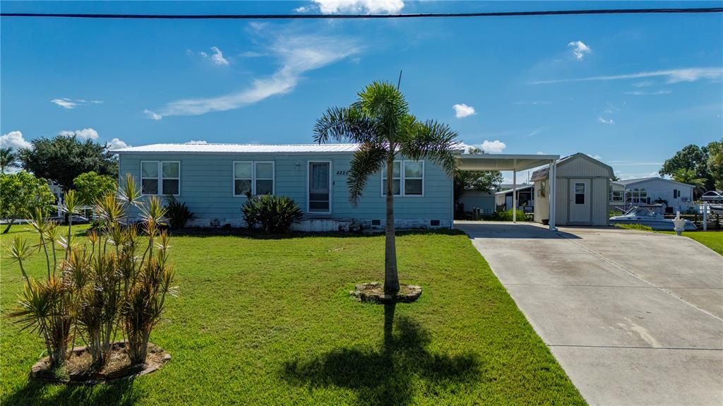 A light blue single-story house features a palm tree, a carport, and a storage shed — 4220 DELTONA DRIVE, PUNTA GORDA, FL