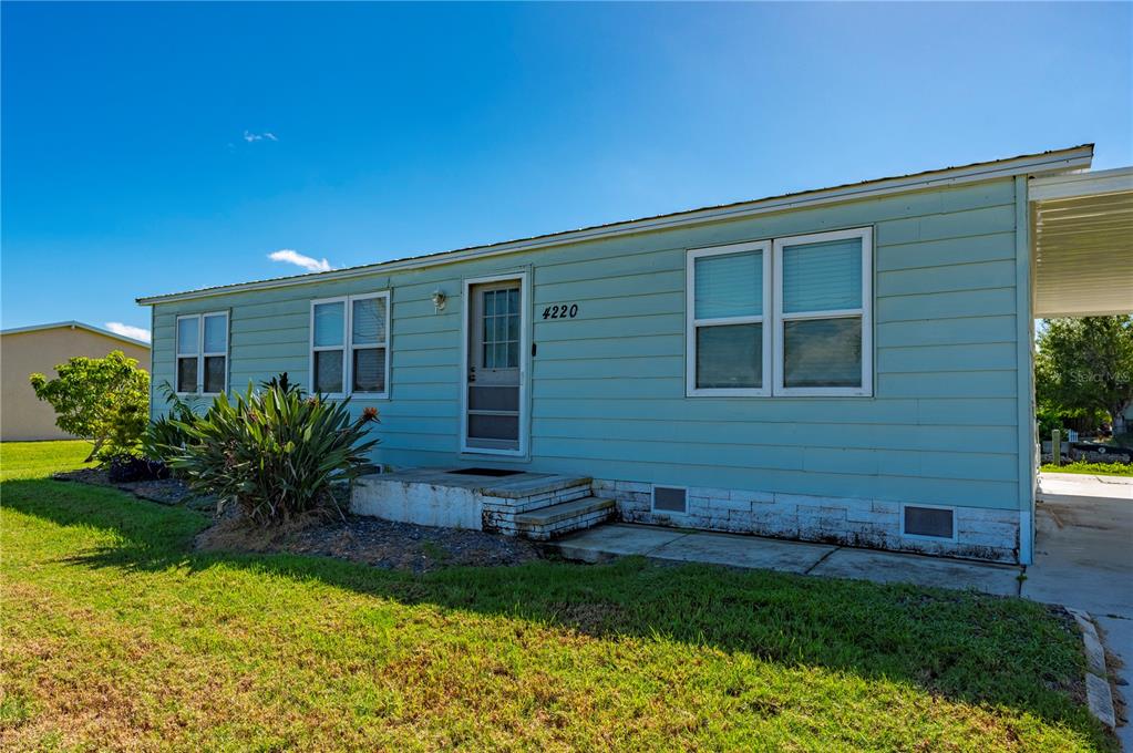 A light blue manufactured home with a front entrance, stairs, and a carport — 4220 DELTONA DRIVE, PUNTA GORDA, FL