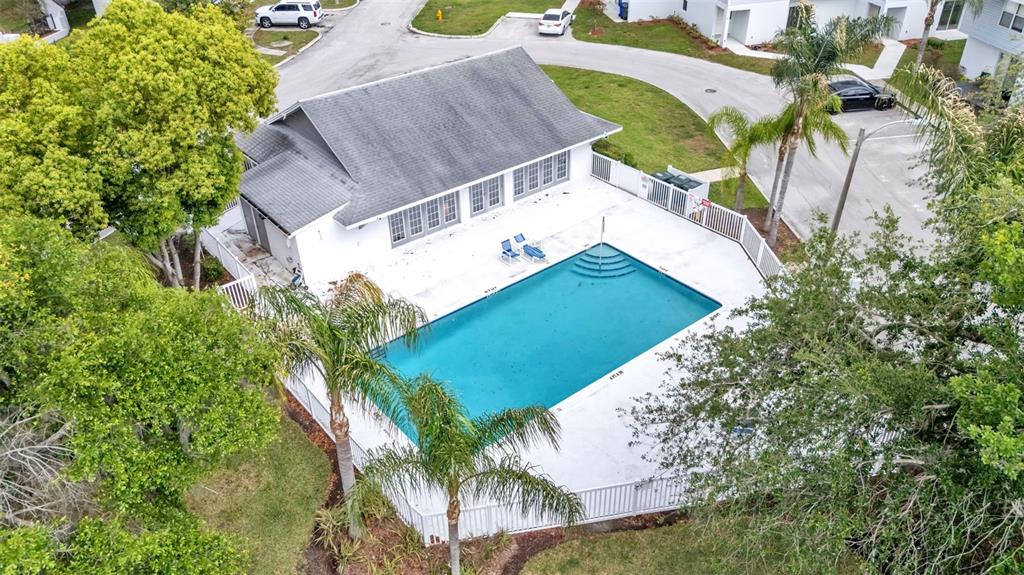 An aerial view shows a rectangular swimming pool with a white deck and adjacent clubhouse — 222 CARPENTERS WAY UNIT 62, LAKELAND, FL
