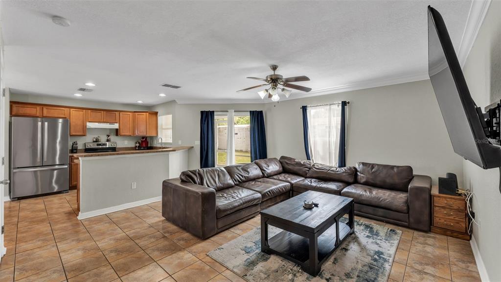 A living room with a brown sectional sofa, coffee table, and an open-concept kitchen — 222 CARPENTERS WAY UNIT 62, LAKELAND, FL