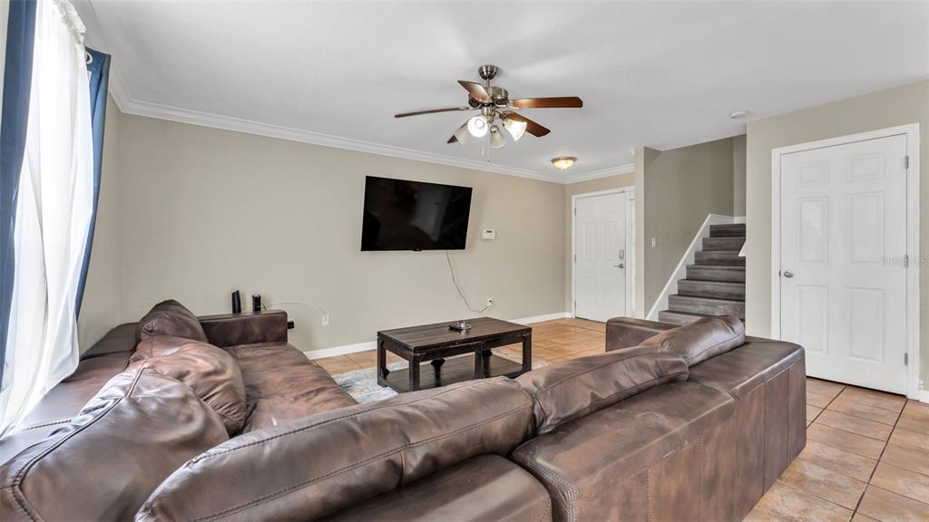 A living room features a large brown sectional sofa, a coffee table, and a wall-mounted television — 222 CARPENTERS WAY UNIT 62, LAKELAND, FL