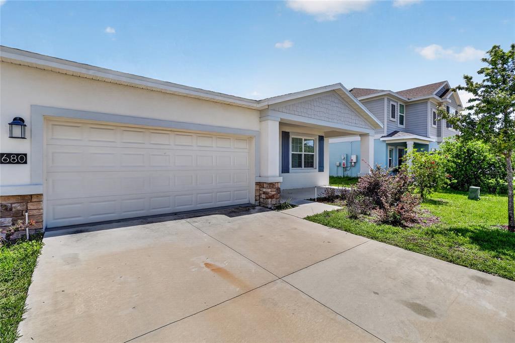 A single-story house exterior features a two-car garage, a covered entryway, and a concrete driveway — 680 GROVE STREET, WINTER HAVEN, FL