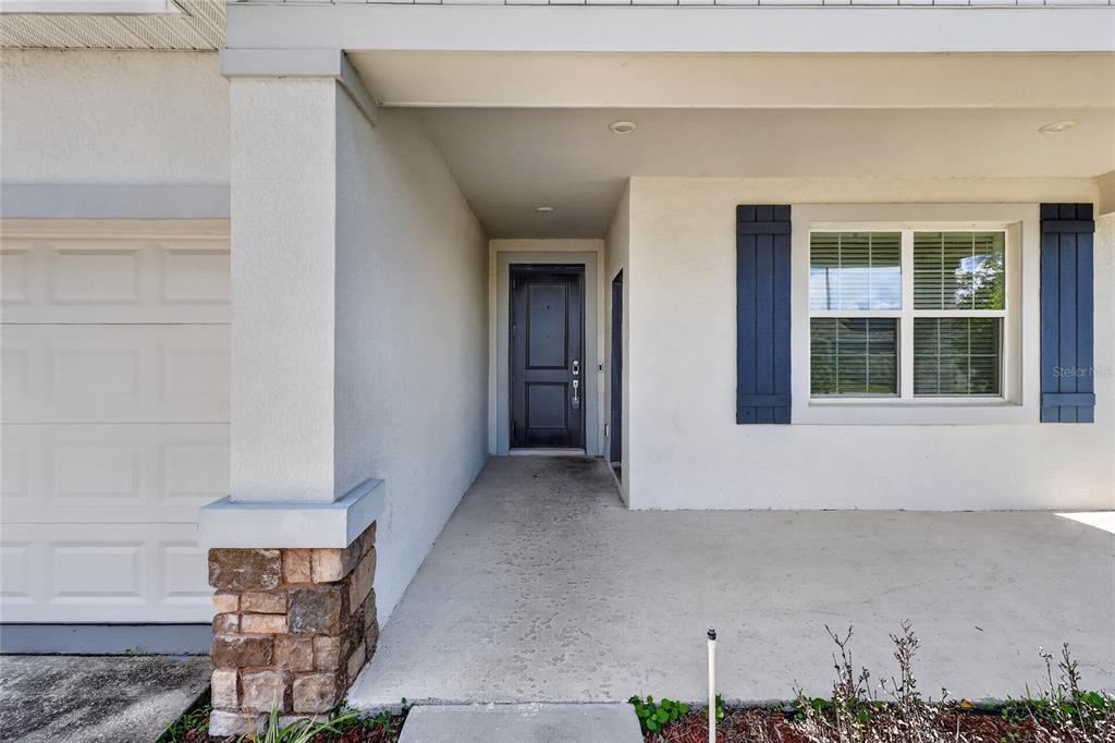 A covered entryway features a dark front door, a window with blue shutters, and stone accents — 680 GROVE STREET, WINTER HAVEN, FL