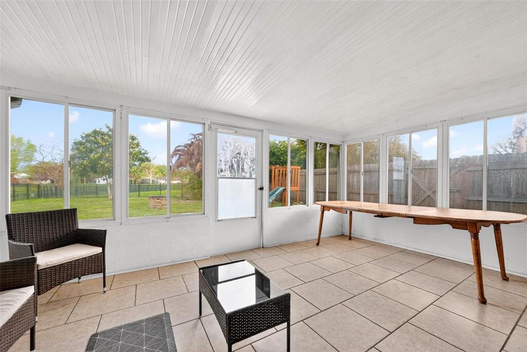 A sunroom with tile flooring, large windows, a white ceiling, and a wooden table — 5107 DEER CREEK DRIVE, ORLANDO, FL