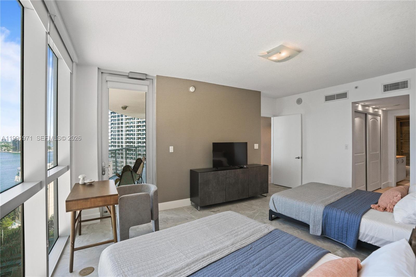 A bedroom features two beds, a television console, a desk, and a balcony with water views — 1750 N Bayshore Dr # 1401, Miami FL 33132, MIAMI, FL
