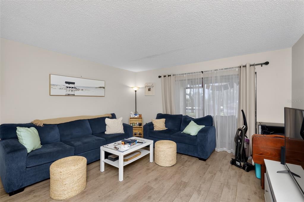 A living room features two blue sofas, a white coffee table, and light wood flooring — 2650 COUNTRYSIDE BOULEVARD UNIT B104, CLEARWATER, FL