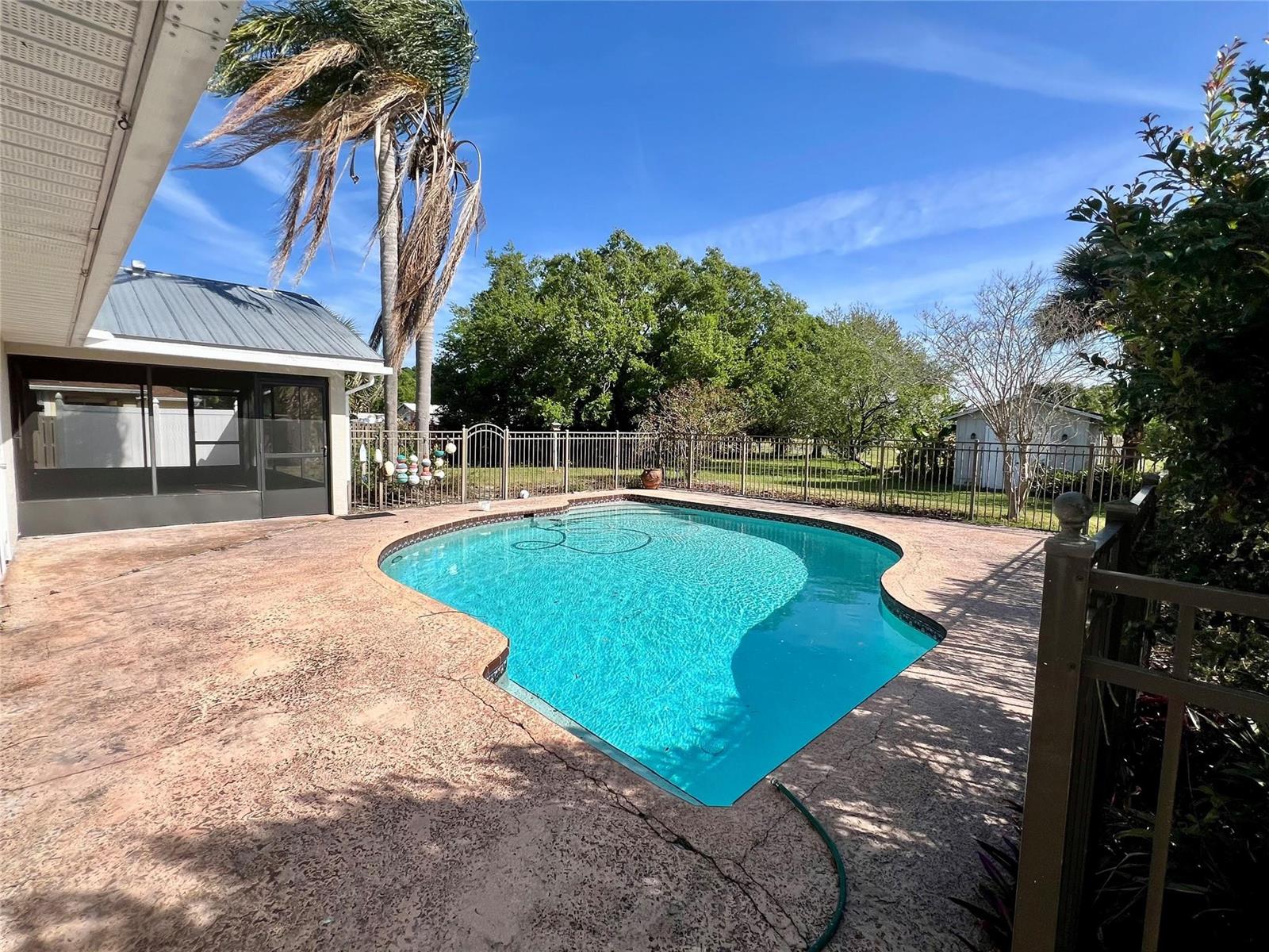 A backyard swimming pool with a concrete deck, screened patio, and metal fencing — 352 SW 85th Avenue, Okeechobee FL 34974, OKEECHOBEE, FL