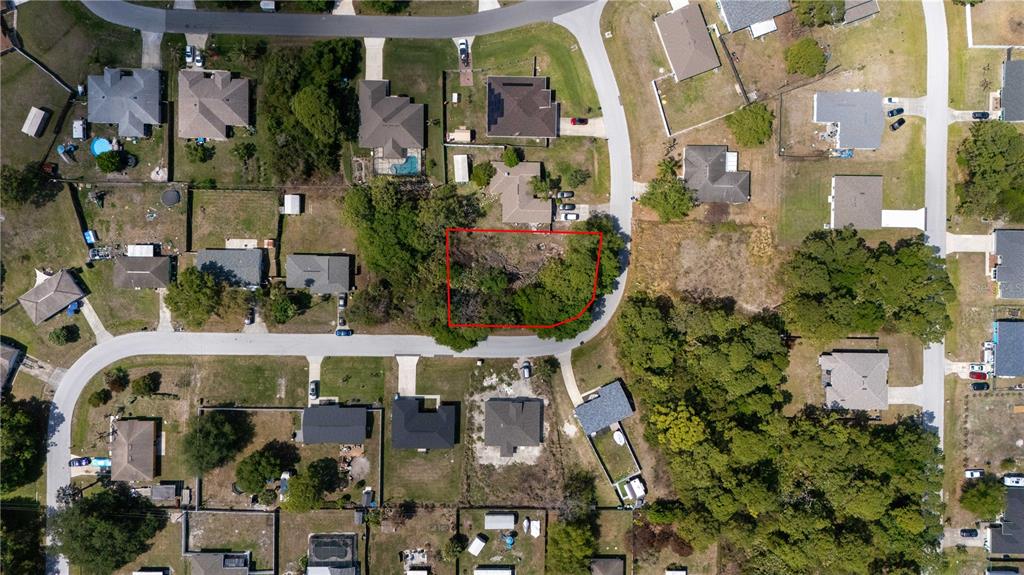 This aerial view shows a vacant, tree-covered residential lot outlined in red within a neighborhood — 1140 YAGER SE, PALM BAY, FL