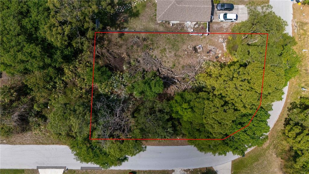 An aerial view shows a rectangular, partially wooded vacant lot outlined in red — 1140 YAGER SE, PALM BAY, FL
