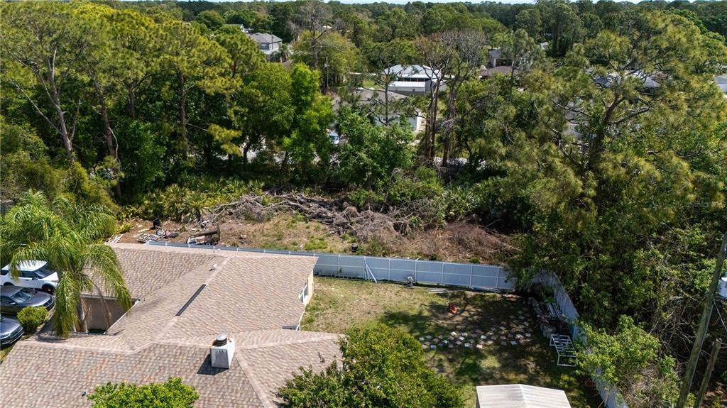 An aerial view shows a residential backyard with a white fence and adjacent wooded area — 1140 YAGER SE, PALM BAY, FL