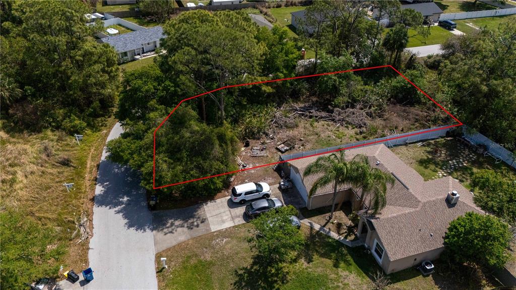 An aerial view shows a vacant, wooded lot outlined in red next to a residential house — 1140 YAGER SE, PALM BAY, FL