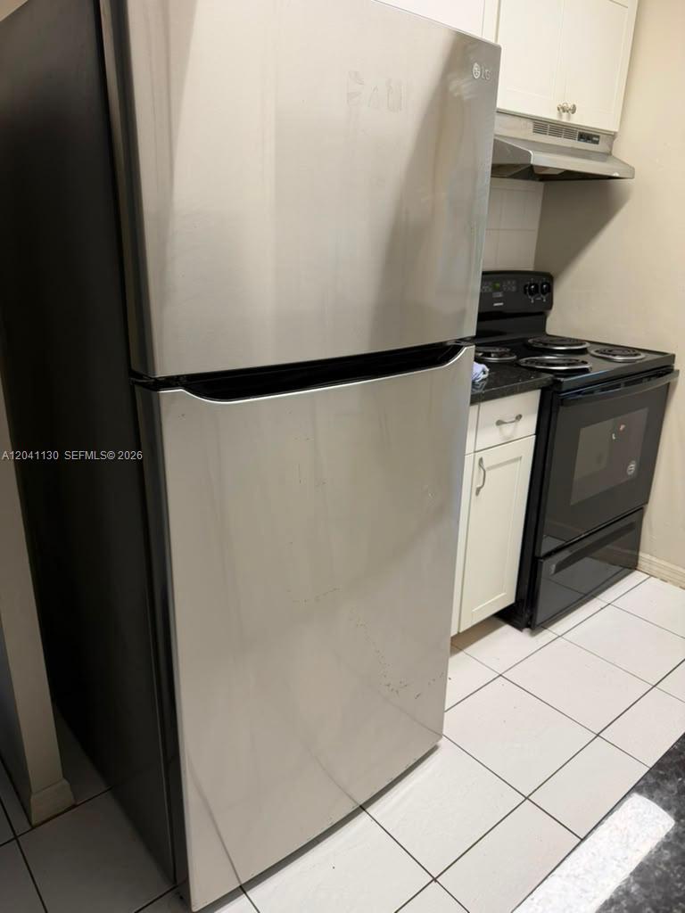 A kitchen features a stainless steel refrigerator, a black electric stove, and white cabinets — 314 S J St # 4, Lake Worth FL 33460, LAKE WORTH, FL