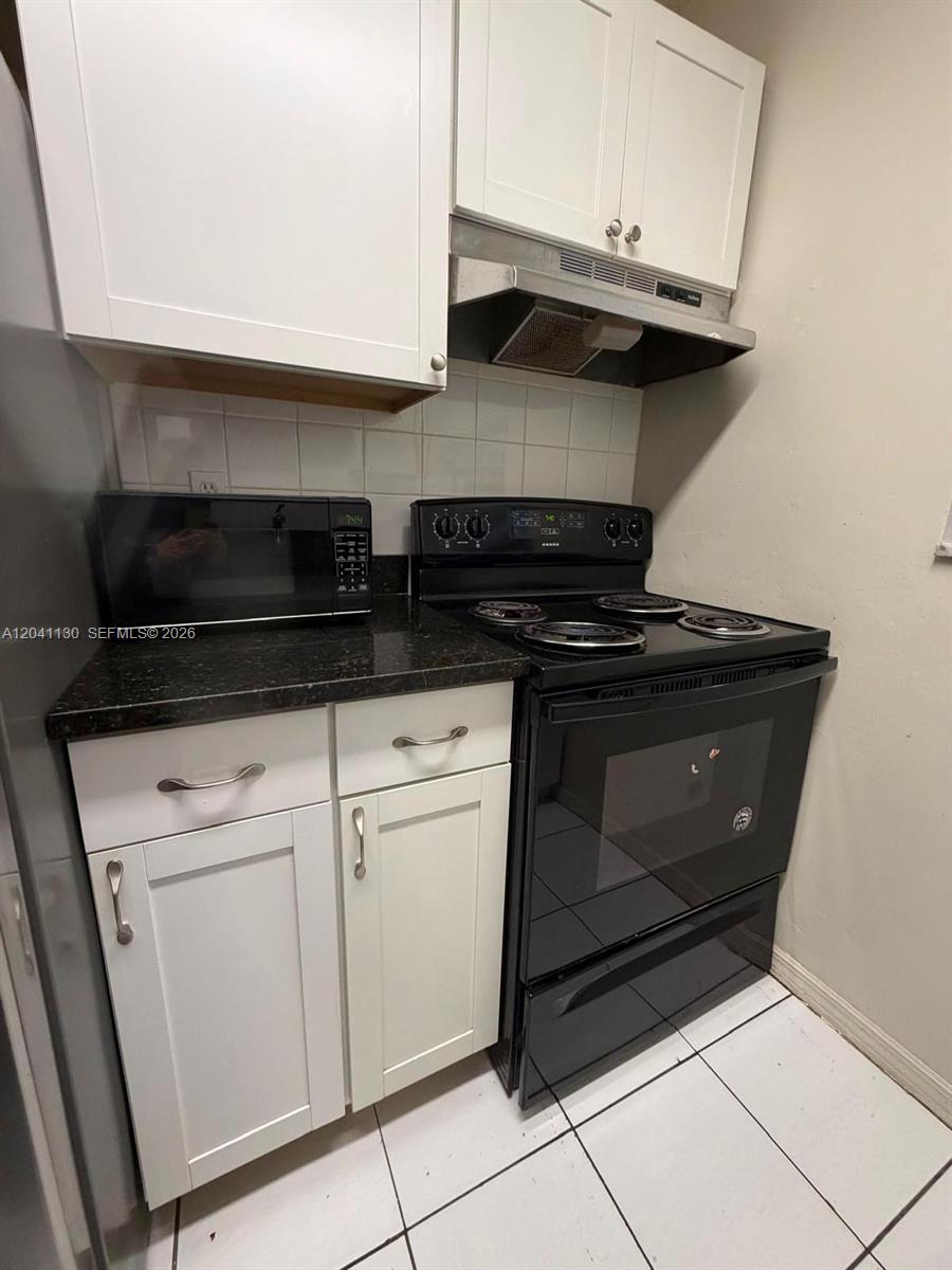 A kitchen features white cabinets, black appliances, and a dark countertop over a tiled floor — 314 S J St # 4, Lake Worth FL 33460, LAKE WORTH, FL