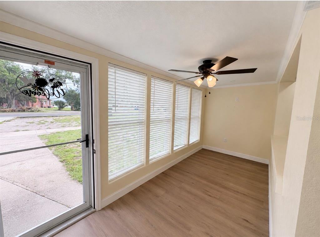 A sunroom features light-colored walls, wood-look flooring, a ceiling fan, and large windows with blinds — 1708 E MAIN STREET, LAKELAND, FL