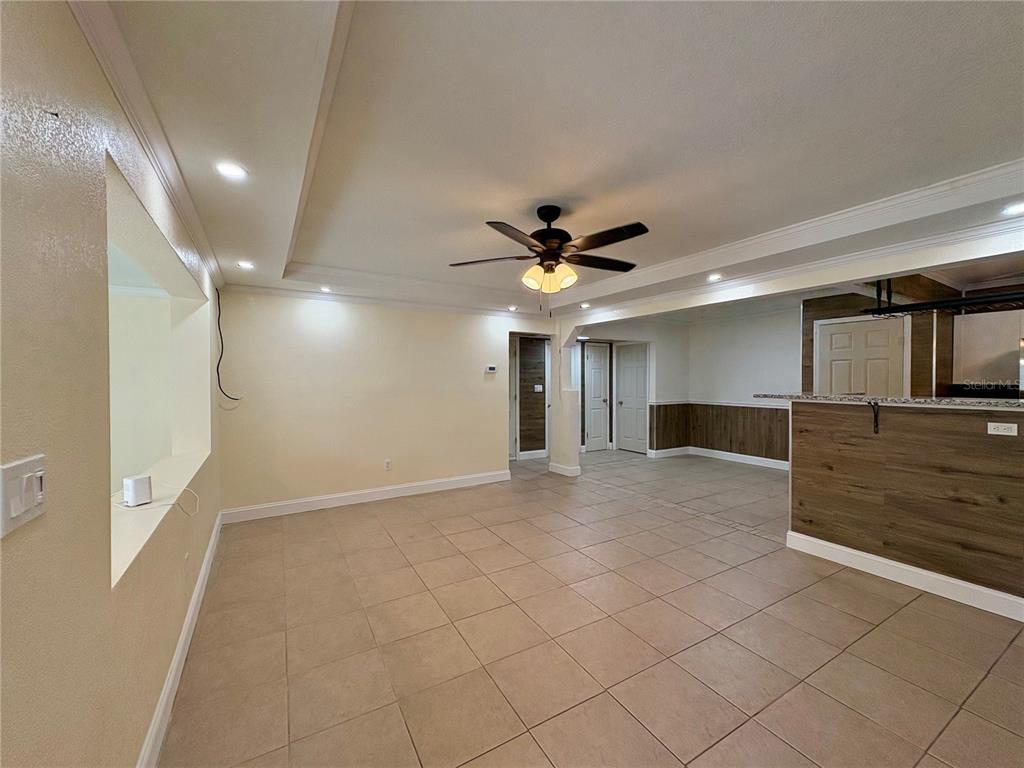 A living area with tile flooring, a ceiling fan, and a wood-paneled breakfast bar — 1708 E MAIN STREET, LAKELAND, FL