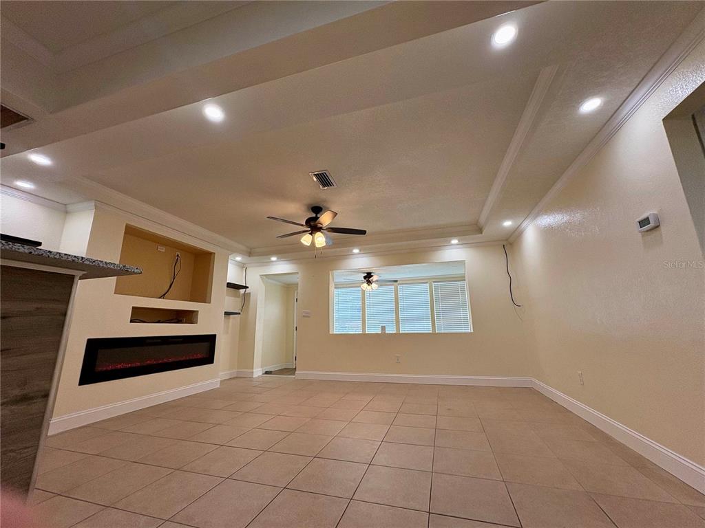 A living room features a tray ceiling, recessed lighting, tile flooring, and a built-in fireplace — 1708 E MAIN STREET, LAKELAND, FL