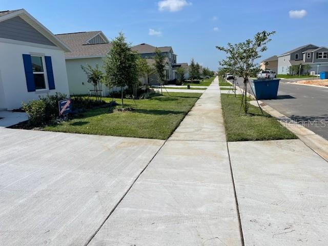 A concrete sidewalk runs between suburban houses and a street with a blue dumpster — 2930 PENNACHIO DRIVE, LAKE WALES, FL