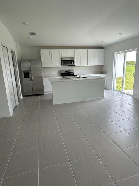 A kitchen with white cabinets, stainless steel appliances, a center island, and light tile flooring — 2930 PENNACHIO DRIVE, LAKE WALES, FL
