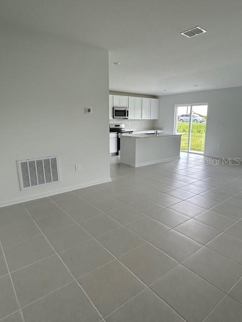 An open-concept kitchen with white cabinets and a center island overlooks a tiled living area — 2930 PENNACHIO DRIVE, LAKE WALES, FL