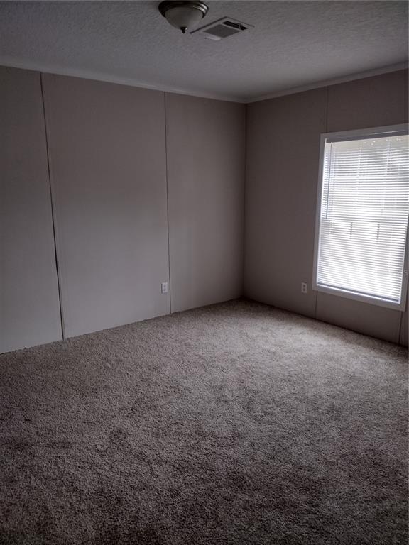 An empty bedroom with beige walls, carpeted flooring, and a window with white blinds — 13144 SW 18TH STREET ROAD, OCALA, FL