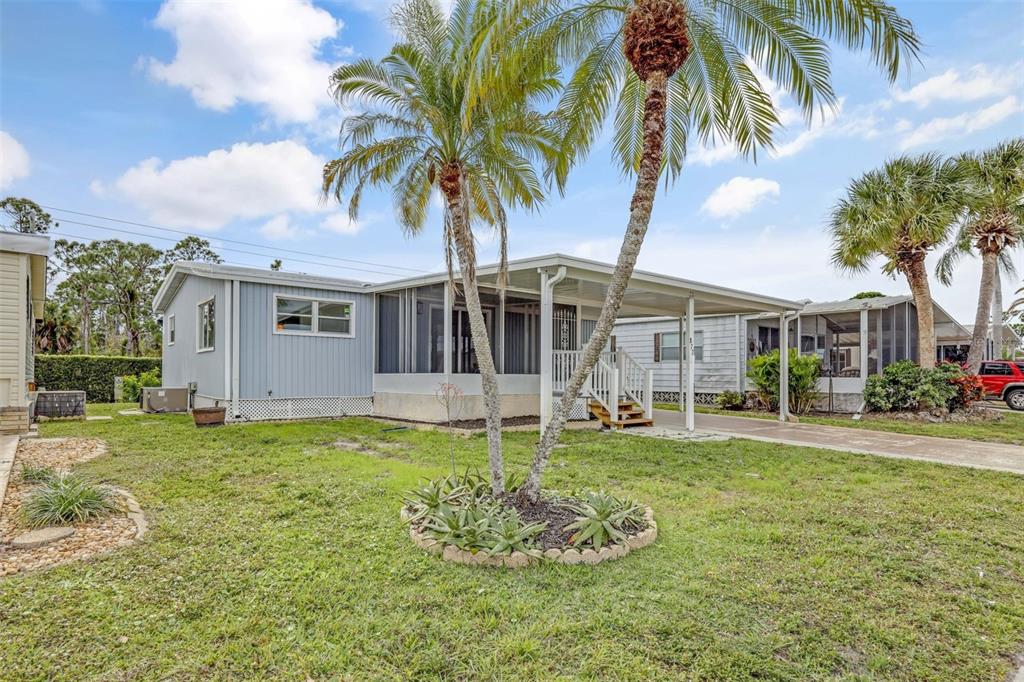 A light blue mobile home features a screened-in porch, a carport, and two palm trees — 2100 KINGS HIGHWAY UNIT 877, PORT CHARLOTTE, FL