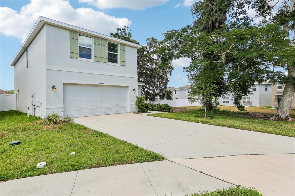 A two-story house with a white stucco exterior, a two-car garage, and a concrete driveway — 36557 NIGHT STRAWBERRY COURT, DADE CITY, FL