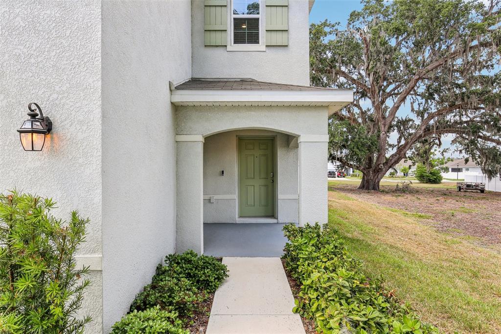 A light-colored house exterior features a covered entryway with a green front door — 36557 NIGHT STRAWBERRY COURT, DADE CITY, FL