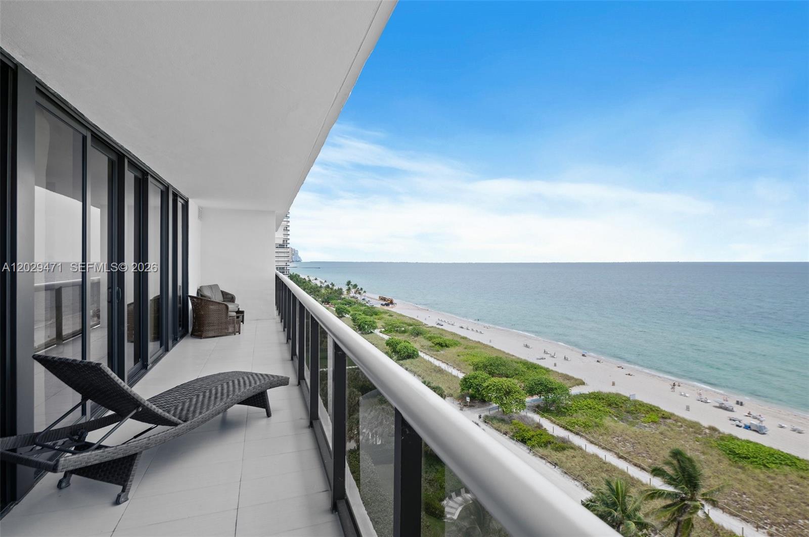 A balcony with a lounge chair overlooks a sandy beach and the ocean — 9455 Collins Ave # 1208, Surfside FL 33154, SURFSIDE, FL